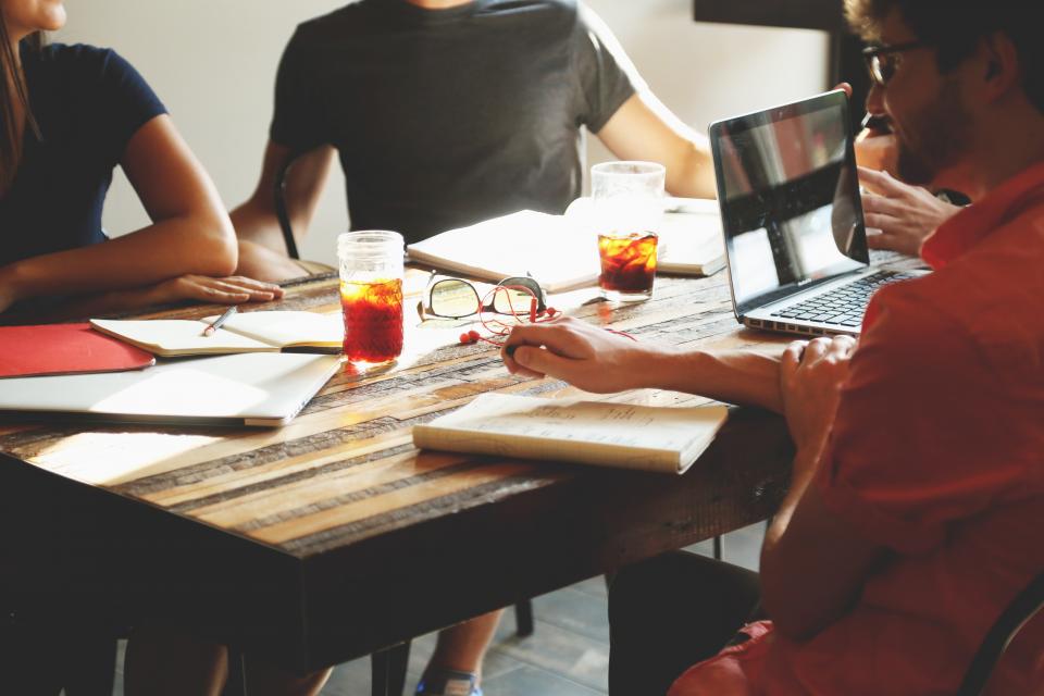 A small team around a table with a laptop and notebooks